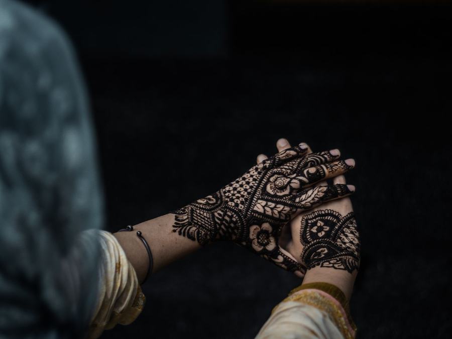 Intricate dark henna design across the back of a hand